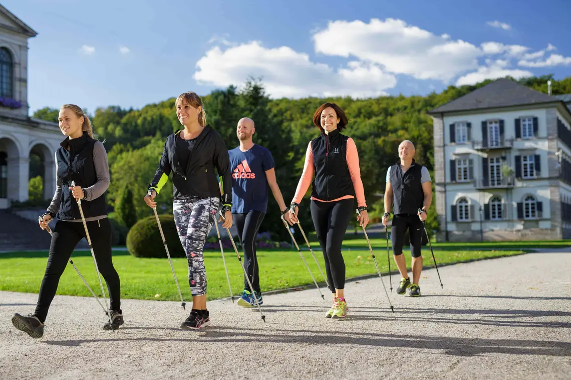 Fünf Personen beim Nordic Walking auf dem Klinikgelände der Dr. von Weckbecker Klinik