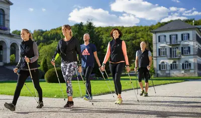 Fünf Personen beim Nordic Walking auf dem Klinikgelände der Dr. von Weckbecker Klinik
