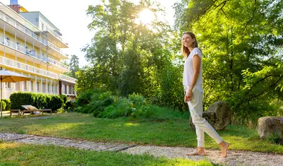 Frau spaziert durch den Park der Dr. von Weckbecker Klinik