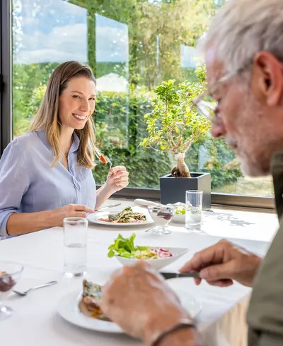 Ein Mann und eine Frau sitzen schräg gegenüber an einem Tisch und essen