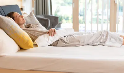 Eine Frau liegt auf einem Bett in der Dr. von Weckbecker Klinik mit einer Leberpackung auf dem Oberkörper