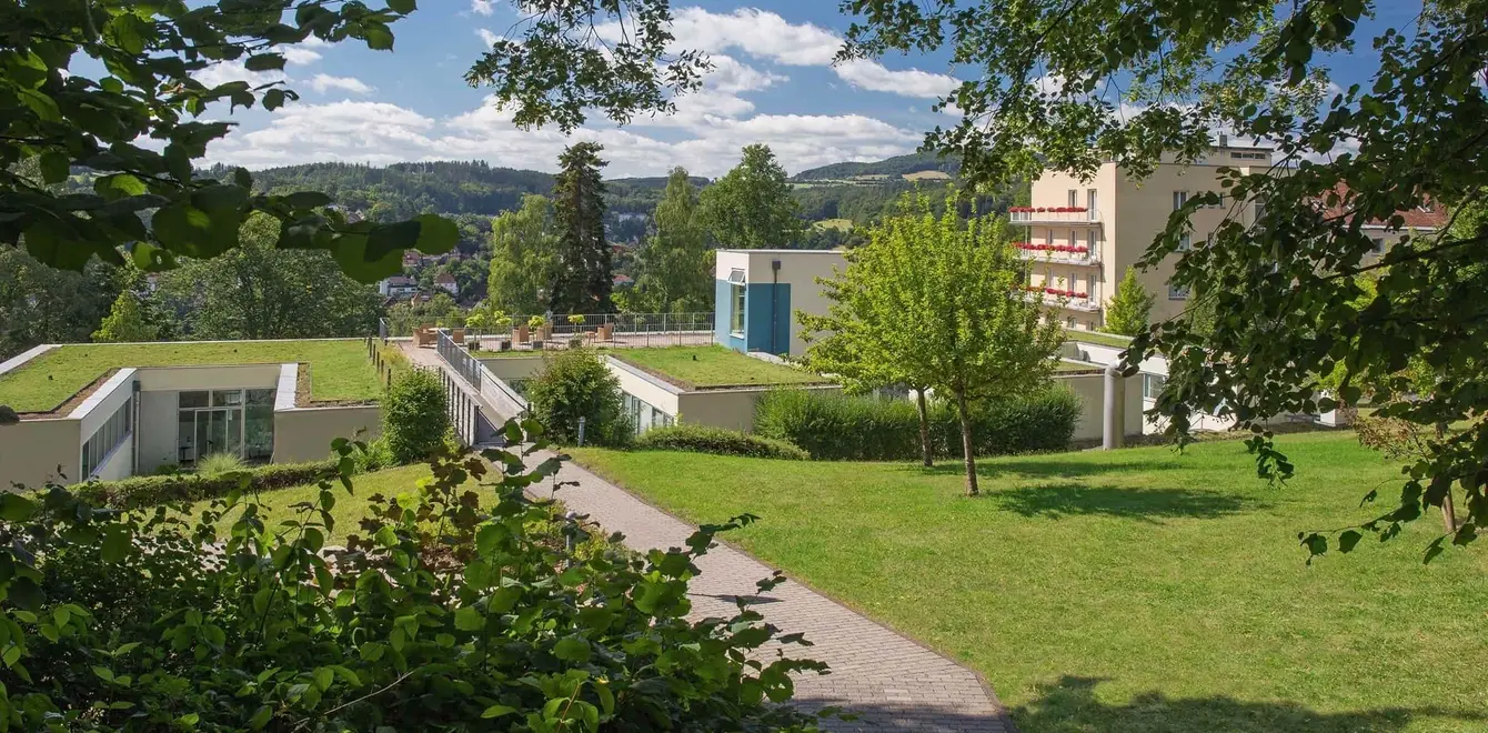Blick durch Bäume auf das Gelände der Weckbecker Klinik
