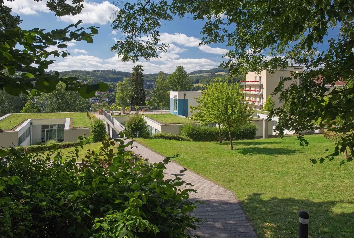 Blick durch Bäume auf das Gelände der Weckbecker Klinik