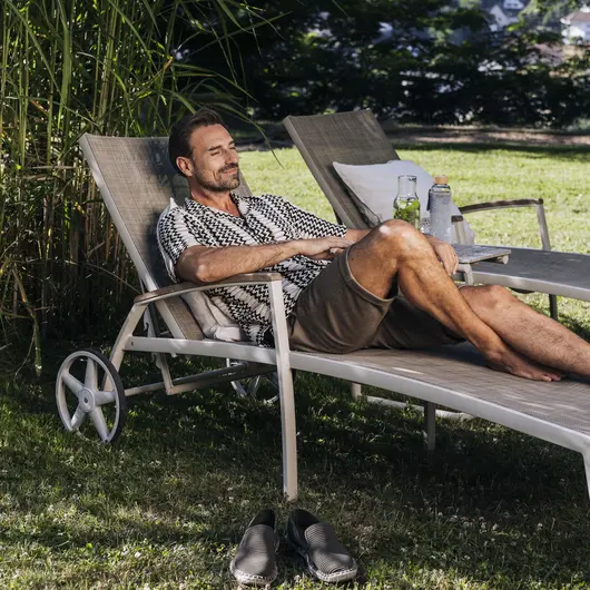 Ein Mann liegt auf einem Liegestuhl im Schatten