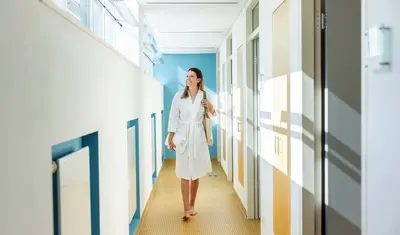 Ein Frau läuft durch einen Gang in der Dr. von Weckbecker Klinik und schaut dabei aus dem Fester Richtung Sonne.