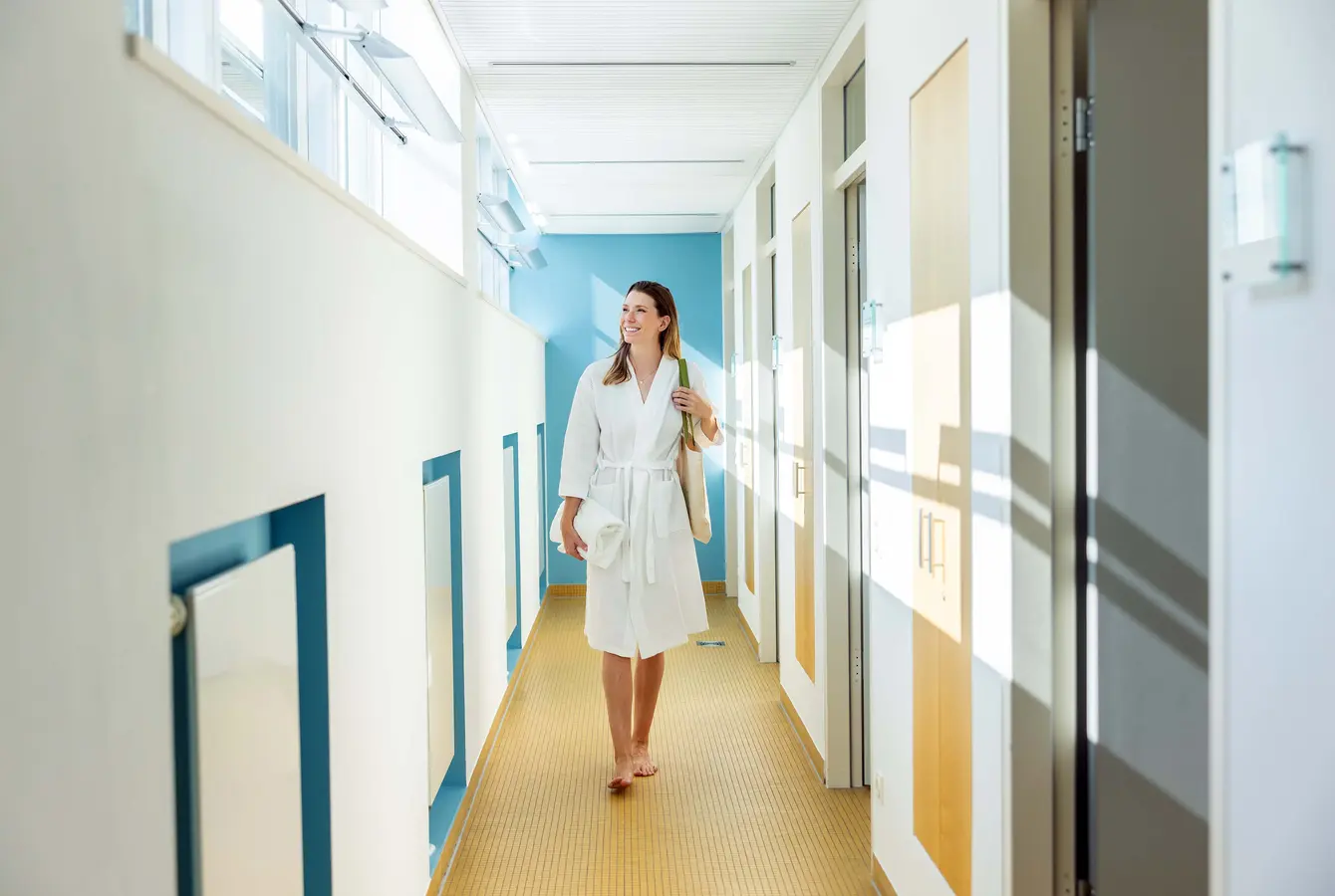 Ein Frau läuft durch einen Gang in der Dr. von Weckbecker Klinik und schaut dabei aus dem Fester Richtung Sonne.