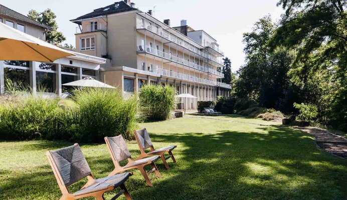 Die Weckbecker Klinik im Hintergrund einer großen Rasenfläche mit 3 Liegestühlen