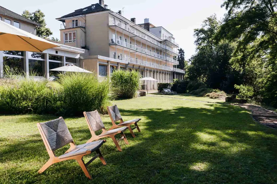 Die Weckbecker Klinik im Hintergrund einer großen Rasenfläche mit 3 Liegestühlen