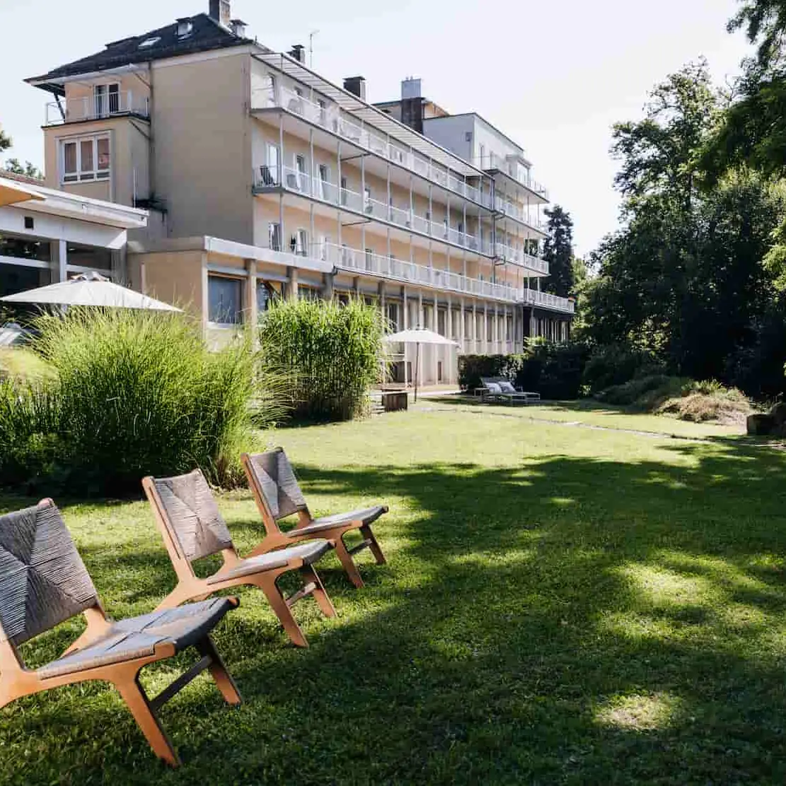 Die Weckbecker Klinik im Hintergrund einer großen Rasenfläche mit 3 Liegestühlen