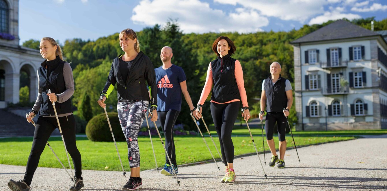 Fünf Personen beim Nordic Walking auf dem Klinikgelände der Dr. von Weckbecker Klinik