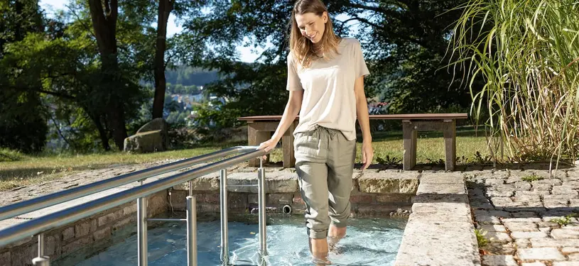 Eine Frau geht durch ein Wasserbecken im Freien