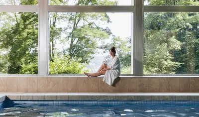 Frau sitzt am Fenster in der hauseigenen Schwimmhalle